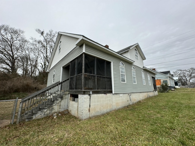 view of side of property featuring a lawn and a sunroom