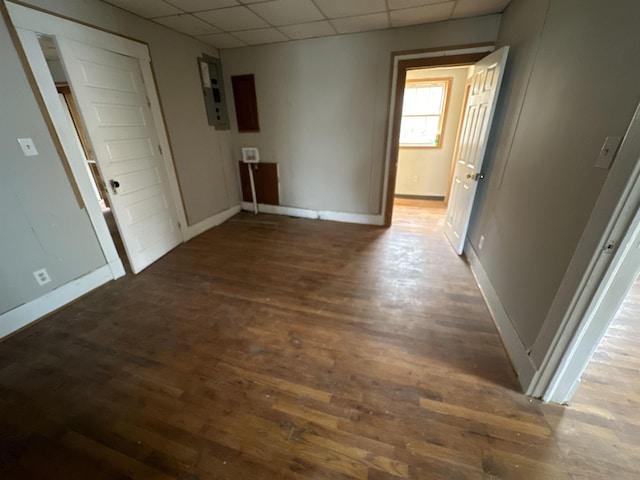 hall with a drop ceiling, electric panel, and dark hardwood / wood-style floors