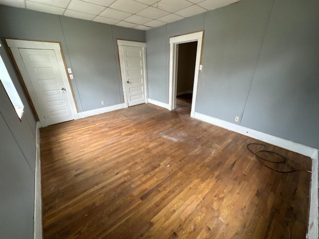 empty room with dark wood-type flooring and a drop ceiling