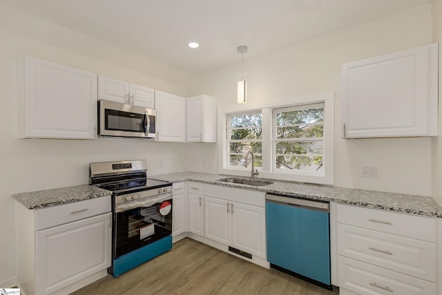 kitchen featuring sink, white cabinetry, hanging light fixtures, stainless steel appliances, and light stone countertops