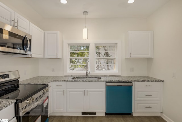 kitchen featuring white cabinetry, appliances with stainless steel finishes, pendant lighting, and light stone counters