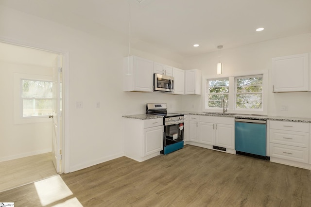 kitchen with hanging light fixtures, appliances with stainless steel finishes, sink, and white cabinets