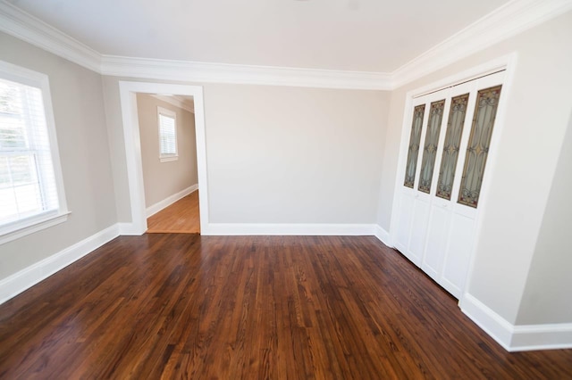 spare room featuring crown molding, dark wood-type flooring, and a wealth of natural light