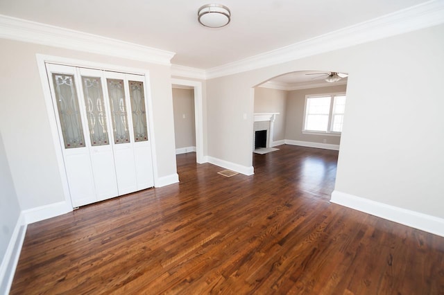 unfurnished living room featuring dark wood-type flooring, ceiling fan, a fireplace, and crown molding