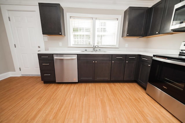 kitchen with ornamental molding, stainless steel appliances, light hardwood / wood-style floors, and sink