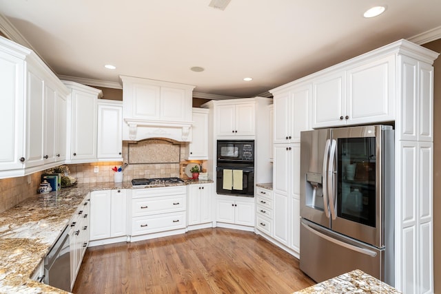 kitchen with black appliances, white cabinetry, ornamental molding, light stone counters, and light hardwood / wood-style floors