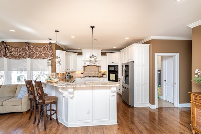 kitchen with a breakfast bar, decorative light fixtures, white cabinets, light stone counters, and black appliances