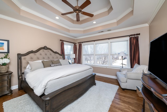 bedroom with dark hardwood / wood-style floors, ornamental molding, and a raised ceiling