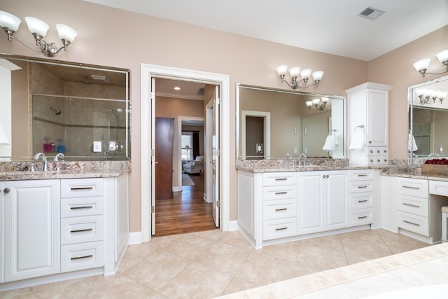 bathroom with tile patterned flooring, vanity, a chandelier, and a shower with shower door