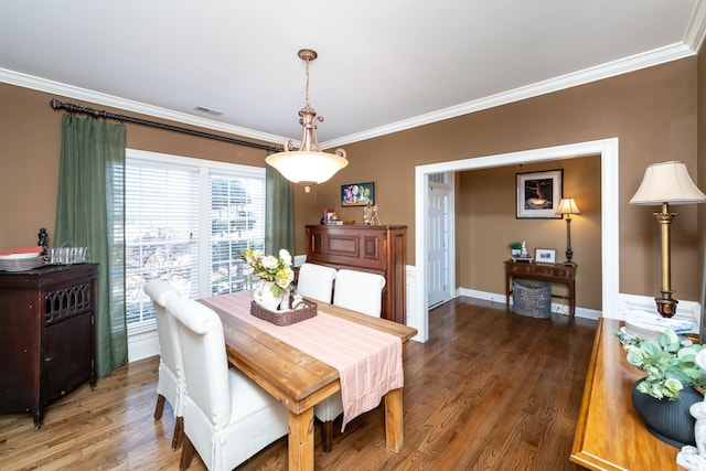 dining area with ornamental molding and dark hardwood / wood-style flooring