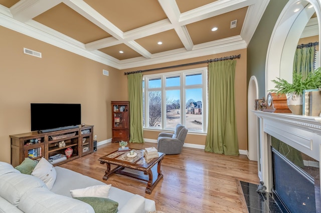 living room featuring beamed ceiling, a premium fireplace, coffered ceiling, and light wood-type flooring