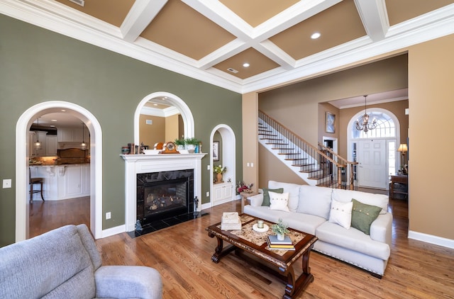 living room featuring beamed ceiling, crown molding, hardwood / wood-style flooring, coffered ceiling, and a premium fireplace