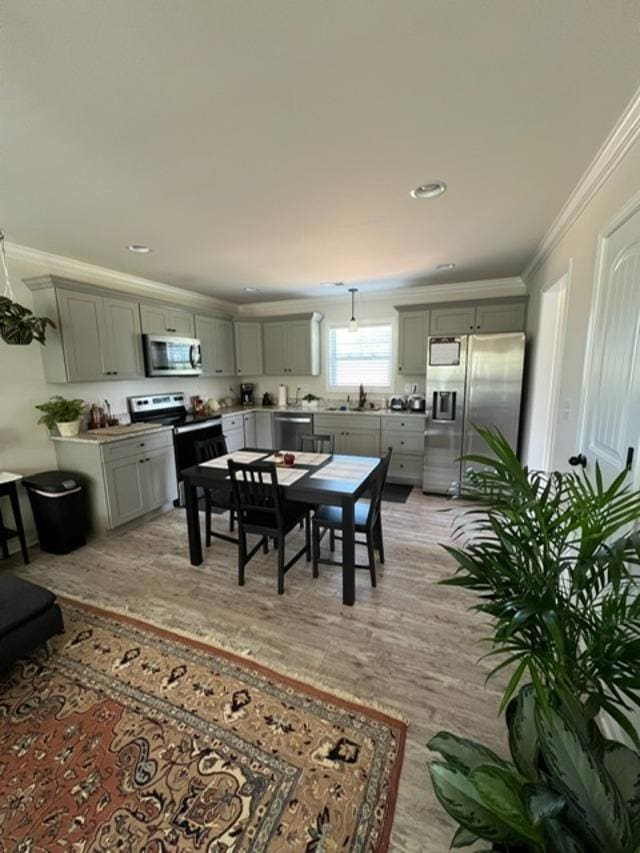 dining space with sink, crown molding, and light hardwood / wood-style floors