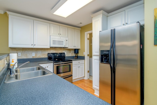 kitchen with sink, stainless steel appliances, tasteful backsplash, white cabinets, and light wood-type flooring