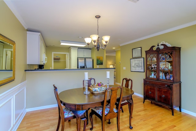 dining space featuring an inviting chandelier, light hardwood / wood-style flooring, and ornamental molding