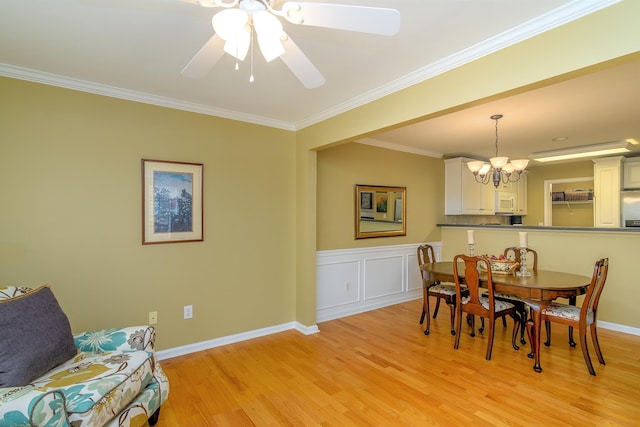 dining area with ceiling fan with notable chandelier, ornamental molding, and light wood-type flooring