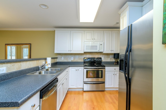 kitchen featuring sink, appliances with stainless steel finishes, white cabinetry, ornamental molding, and kitchen peninsula