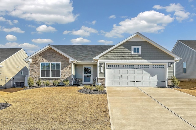 view of front of home featuring a garage, a front yard, and central AC unit