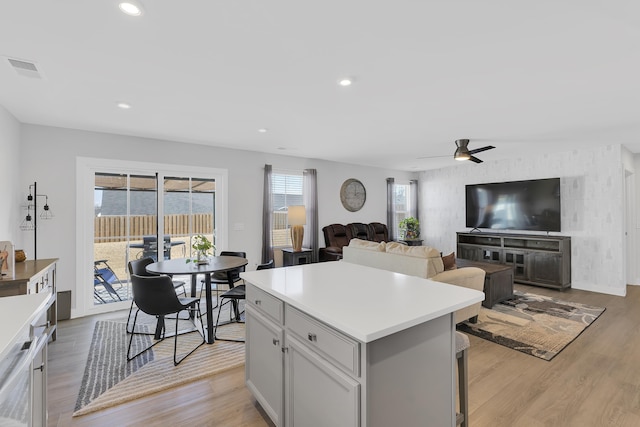 kitchen with light hardwood / wood-style floors, a center island, and ceiling fan