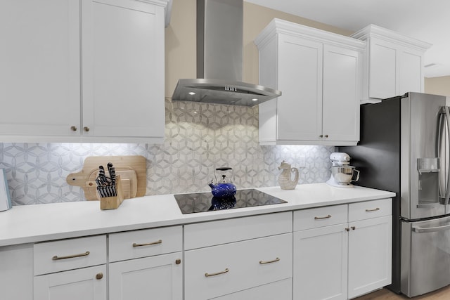 kitchen with black electric stovetop, white cabinets, wall chimney exhaust hood, and stainless steel refrigerator with ice dispenser