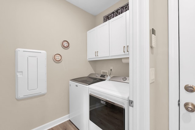 clothes washing area with light hardwood / wood-style flooring, washer and clothes dryer, and cabinets