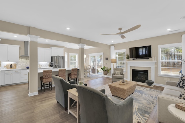 living room featuring hardwood / wood-style floors, ceiling fan, and ornate columns