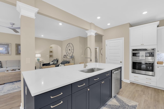 kitchen featuring sink, light hardwood / wood-style flooring, white cabinetry, stainless steel appliances, and a center island with sink