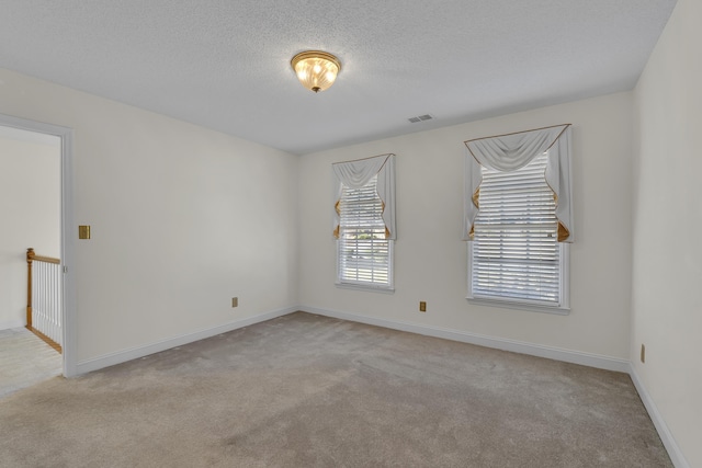 spare room with light colored carpet and a textured ceiling