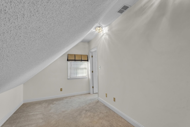 additional living space with light colored carpet, vaulted ceiling, and a textured ceiling