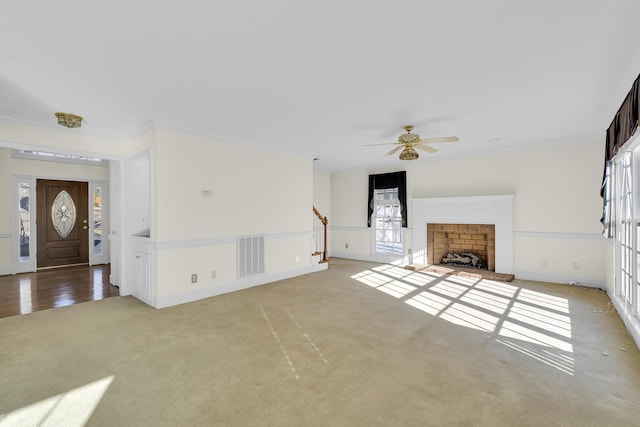 unfurnished living room with crown molding, light carpet, ceiling fan, and a fireplace