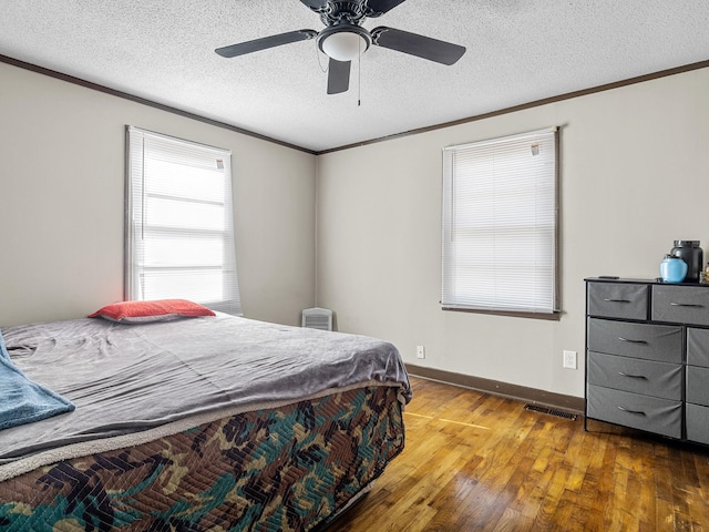 bedroom with ceiling fan, crown molding, a textured ceiling, and hardwood / wood-style flooring