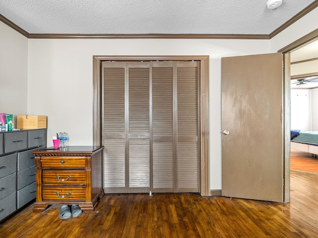 bedroom with crown molding, dark wood-type flooring, a closet, and a textured ceiling