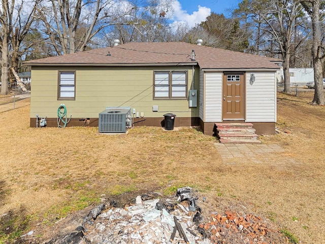 rear view of property with central AC unit and a lawn