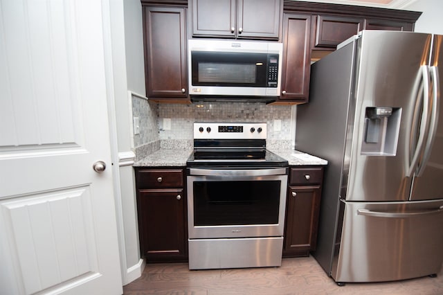 kitchen with light stone counters, appliances with stainless steel finishes, and dark brown cabinets