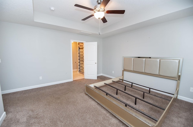 unfurnished bedroom with a raised ceiling, ceiling fan, and carpet flooring