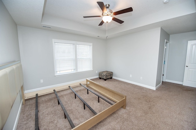 unfurnished room with ceiling fan, carpet floors, a textured ceiling, and a tray ceiling