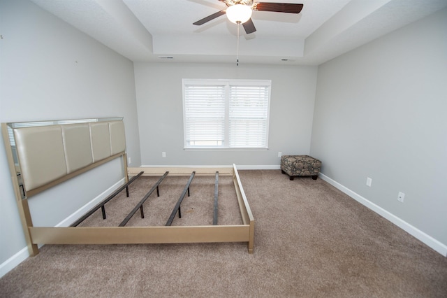 unfurnished bedroom featuring a raised ceiling, carpet, and ceiling fan