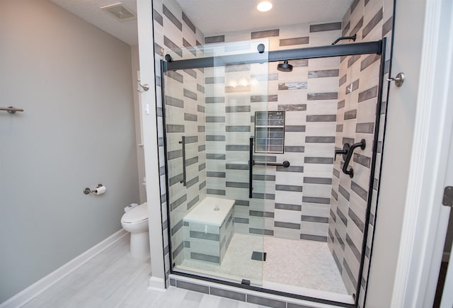 bathroom featuring a shower with shower door and toilet