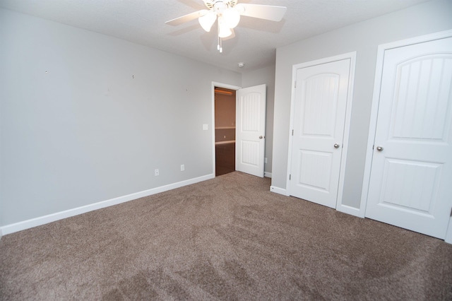 unfurnished bedroom with two closets, ceiling fan, and carpet flooring