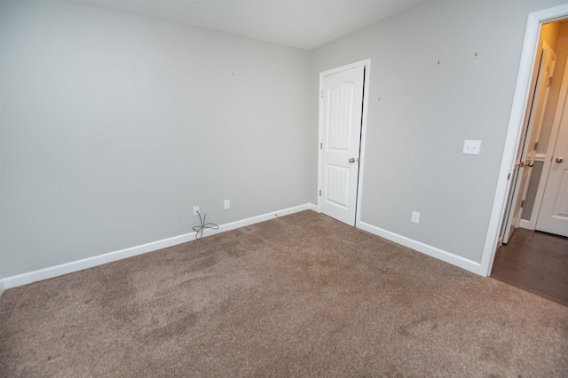 spare room featuring dark colored carpet