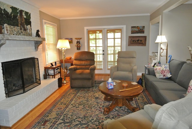 living room featuring a fireplace, crown molding, wood-type flooring, and french doors