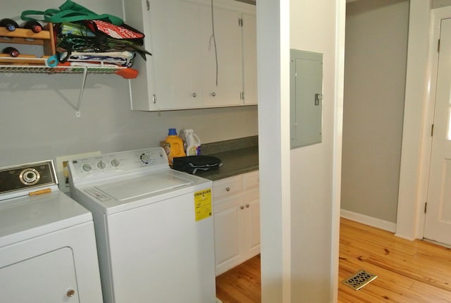 clothes washing area featuring cabinets, electric panel, independent washer and dryer, and light hardwood / wood-style floors