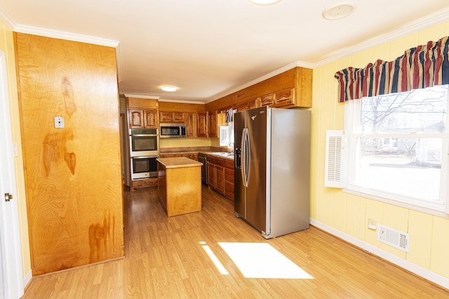 kitchen featuring crown molding, stainless steel appliances, a center island, and light hardwood / wood-style flooring