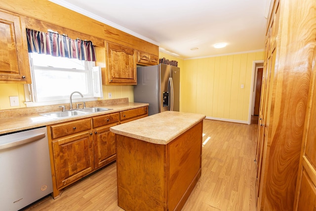 kitchen with sink, light hardwood / wood-style flooring, ornamental molding, a kitchen island, and stainless steel appliances