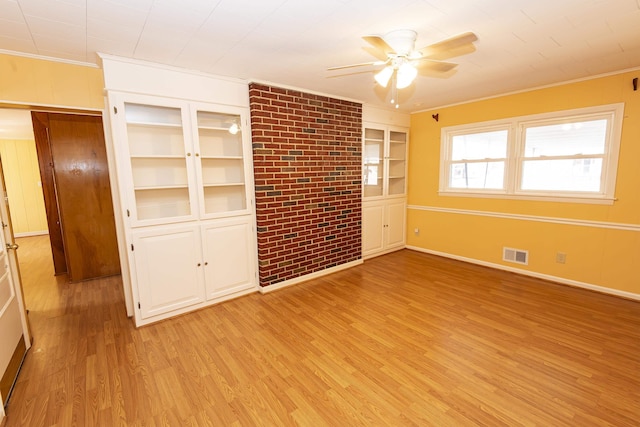 empty room featuring crown molding, built in features, ceiling fan, and light hardwood / wood-style flooring