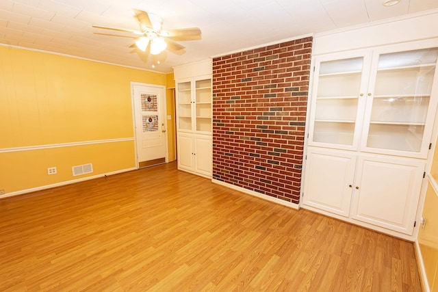 spare room with ornamental molding, built in features, ceiling fan, and light wood-type flooring