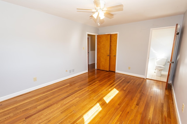 unfurnished bedroom featuring ceiling fan, ensuite bathroom, and hardwood / wood-style floors