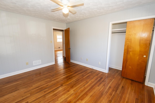 unfurnished bedroom featuring ceiling fan, dark hardwood / wood-style flooring, a closet, and a textured ceiling