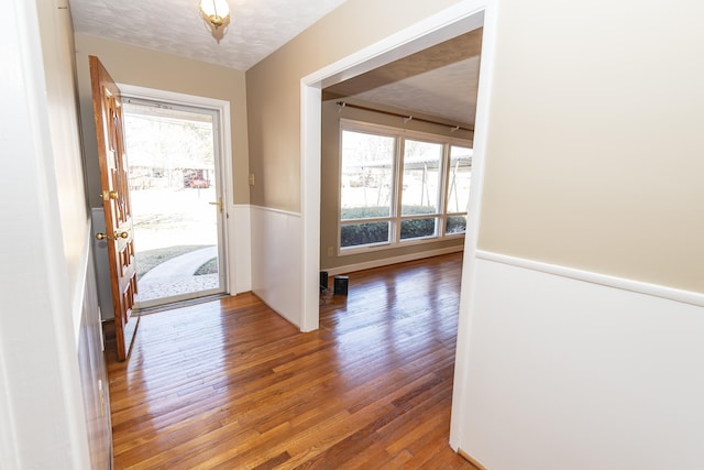 foyer entrance with hardwood / wood-style flooring, plenty of natural light, and a textured ceiling