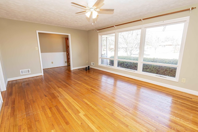 empty room with hardwood / wood-style flooring, ceiling fan, and a textured ceiling